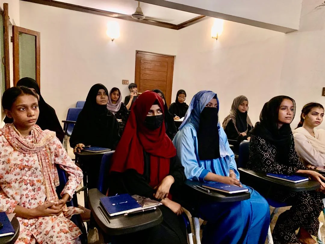 SOCH students listening with notebooks during a session in Karachi.