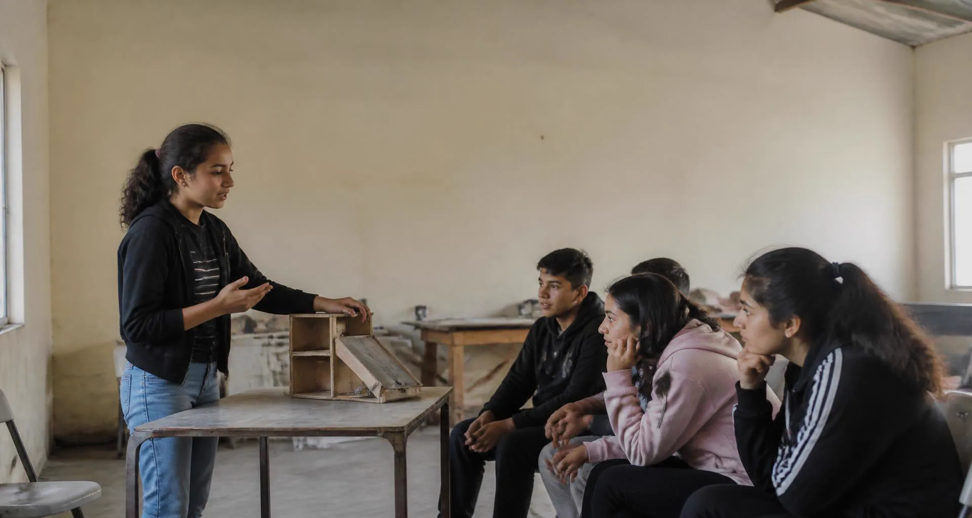 A student demonstrating her prototype to a small audience, mid-question
